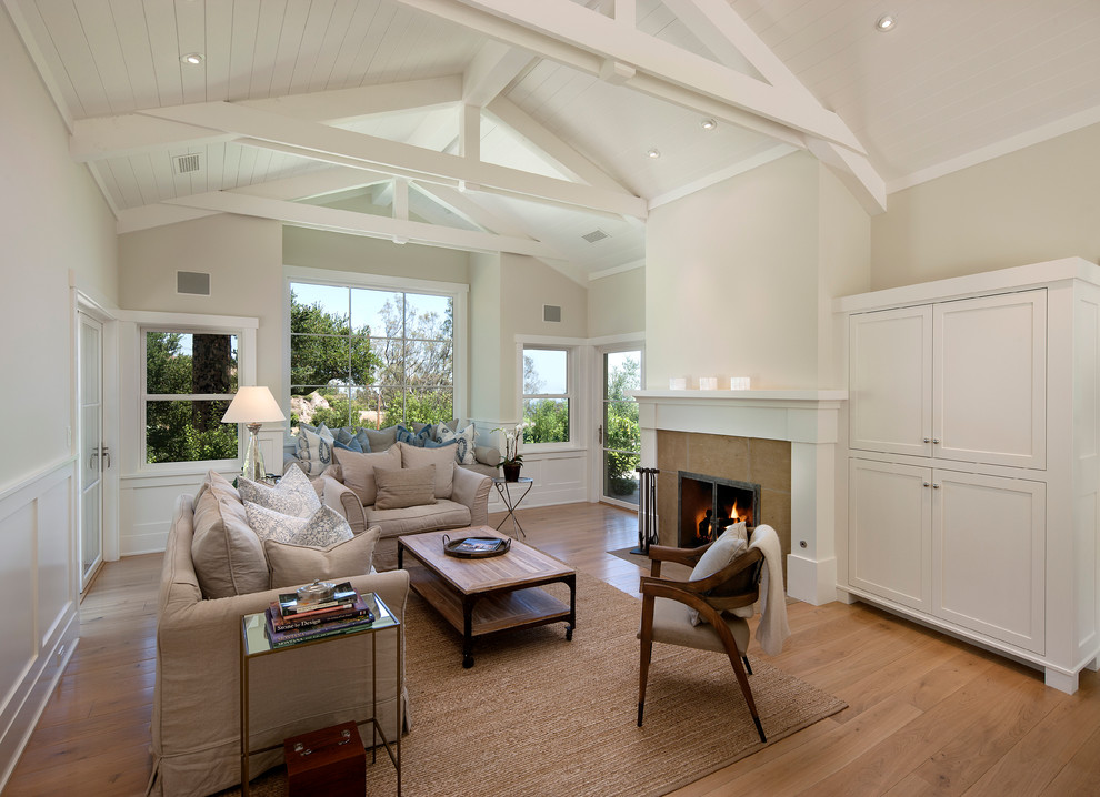 Photo of a large traditional formal open concept living room in Santa Barbara with a standard fireplace, a tile fireplace surround, beige walls, light hardwood floors and no tv.