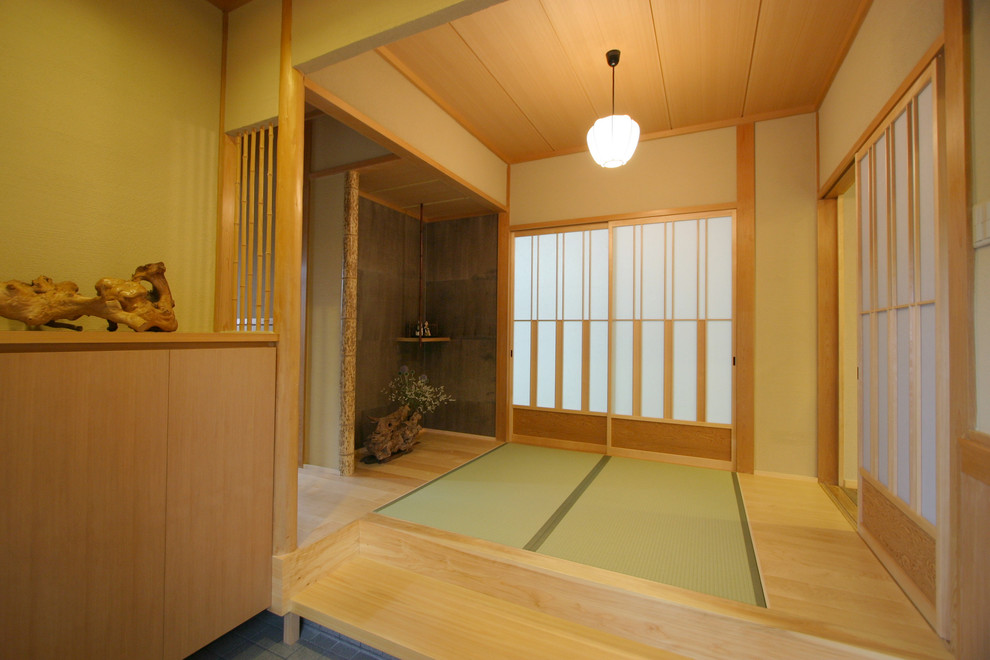 Photo of a mid-sized asian entry hall in Osaka with tatami floors, beige walls, a sliding front door, a medium wood front door and brown floor.