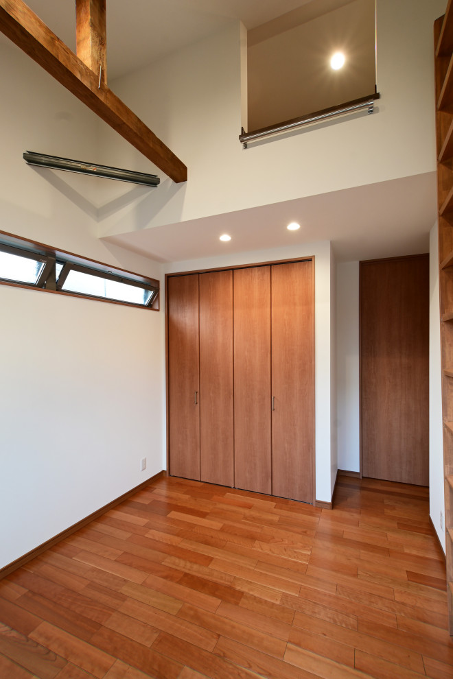 Cette image montre un dressing minimaliste en bois brun de taille moyenne avec un placard à porte affleurante, un sol en bois brun, un sol blanc et un plafond en papier peint.