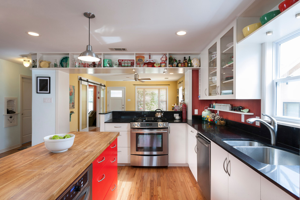 Large transitional l-shaped eat-in kitchen in Austin with a double-bowl sink, glass-front cabinets, white cabinets, stainless steel appliances, quartz benchtops, red splashback, light hardwood floors and multiple islands.