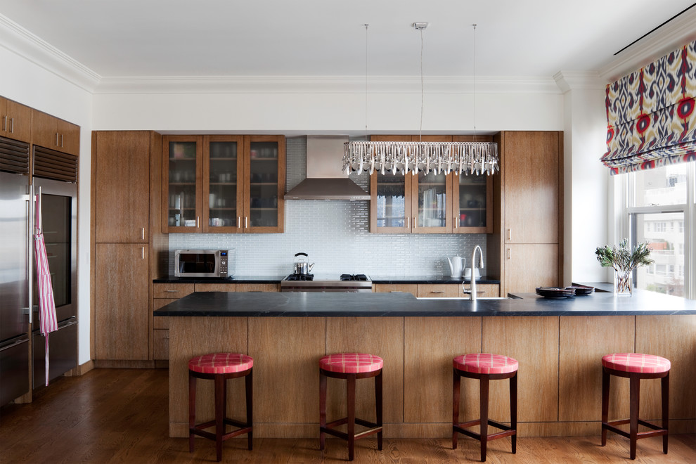 Photo of a mid-sized contemporary u-shaped eat-in kitchen in New York with a farmhouse sink, medium wood cabinets, stainless steel appliances, medium hardwood floors and flat-panel cabinets.