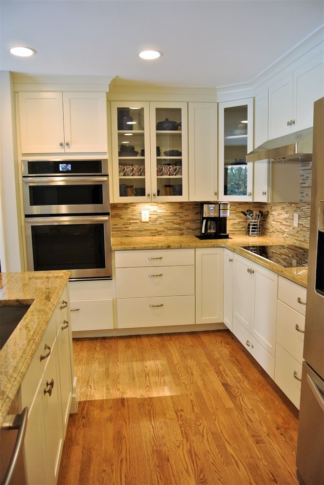 Example of a transitional light wood floor kitchen design in Boston with an undermount sink, shaker cabinets, white cabinets, granite countertops, stainless steel appliances and an island
