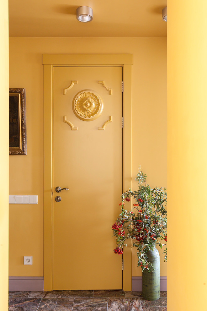 Photo of a small transitional entry hall in Moscow with yellow walls, marble floors and brown floor.