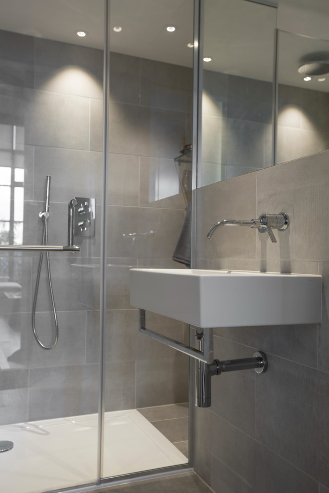 Design ideas for a mid-sized industrial master bathroom in London with shaker cabinets, a drop-in tub, a curbless shower, a wall-mount toilet, white tile, ceramic tile, grey walls, ceramic floors, a drop-in sink and marble benchtops.