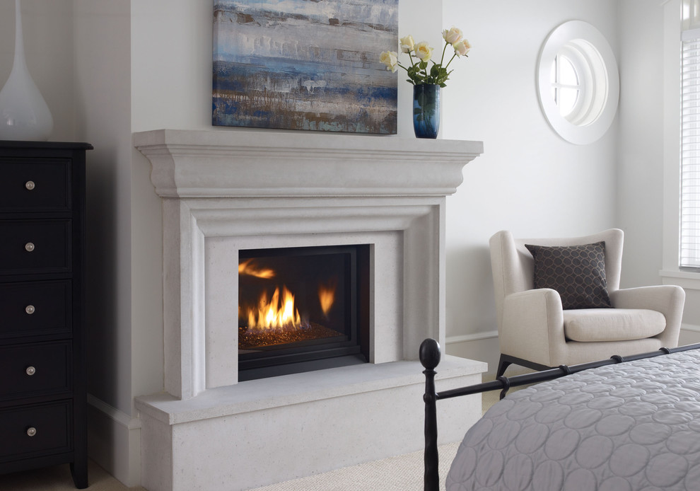This is an example of a small beach style bedroom in Vancouver with white walls, carpet, a standard fireplace and a concrete fireplace surround.