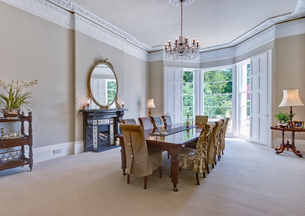 Design ideas for an expansive traditional separate dining room in Devon with beige walls, carpet, a standard fireplace and a stone fireplace surround.