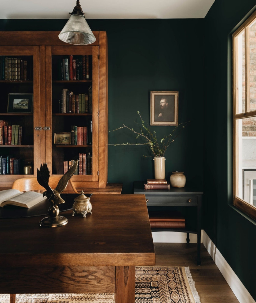 Inspiration for a mid-sized country study room in Other with green walls, medium hardwood floors, a standard fireplace, a stone fireplace surround, a freestanding desk and brown floor.