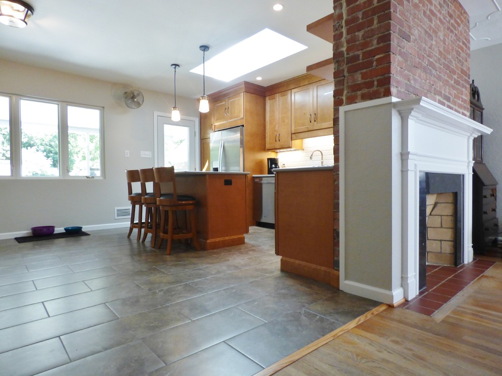 Eat-in kitchen - transitional l-shaped porcelain tile eat-in kitchen idea with an undermount sink, recessed-panel cabinets, medium tone wood cabinets, quartz countertops, white backsplash, subway tile backsplash, stainless steel appliances and an island