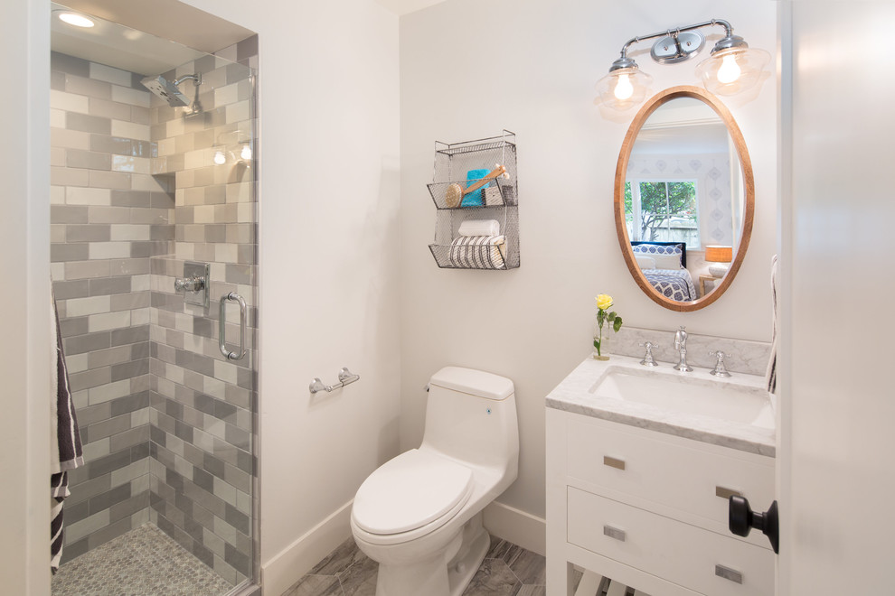 Photo of a small country kids bathroom in San Francisco with flat-panel cabinets, white cabinets, an alcove shower, white tile, gray tile, subway tile, porcelain floors, marble benchtops, a hinged shower door, a one-piece toilet, white walls, an undermount sink and grey floor.