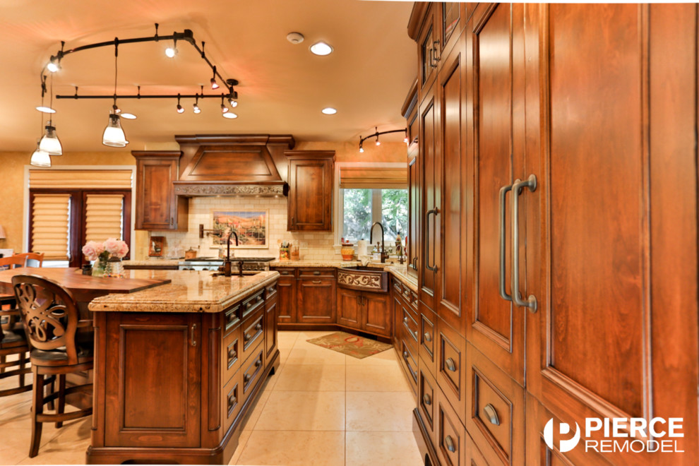 This is an example of a large traditional l-shaped eat-in kitchen in Salt Lake City with an integrated sink, recessed-panel cabinets, medium wood cabinets, granite benchtops, beige splashback, stone tile splashback, panelled appliances, travertine floors and with island.