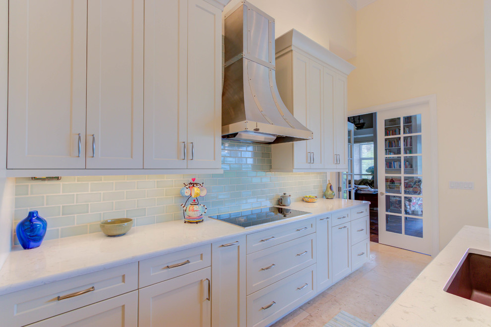 Large transitional single-wall enclosed kitchen photo with an undermount sink, flat-panel cabinets, white cabinets, quartz countertops, blue backsplash, stone tile backsplash, stainless steel appliances and an island