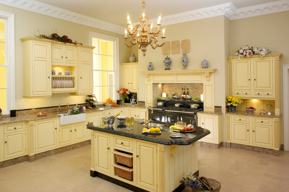 Photo of an expansive traditional u-shaped enclosed kitchen with a submerged sink, raised-panel cabinets, granite worktops, brown splashback, stone slab splashback, integrated appliances, limestone flooring, an island, beige floors and black worktops.