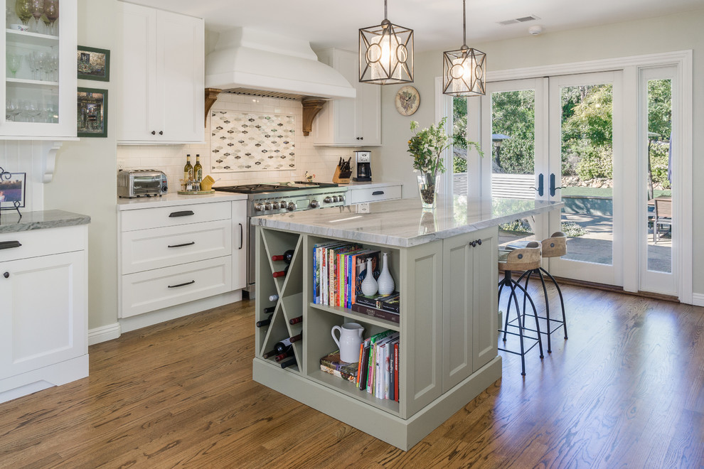 This is an example of a mid-sized traditional kitchen in Los Angeles with recessed-panel cabinets, white cabinets, quartzite benchtops, mosaic tile splashback, stainless steel appliances, medium hardwood floors, with island, multi-coloured splashback and brown floor.