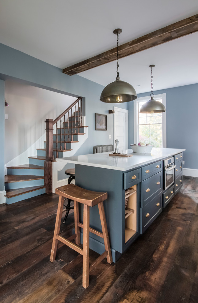 Design ideas for a mid-sized country single-wall separate kitchen in Boston with a farmhouse sink, flat-panel cabinets, white cabinets, soapstone benchtops, white splashback, porcelain splashback, stainless steel appliances, dark hardwood floors, with island and brown floor.