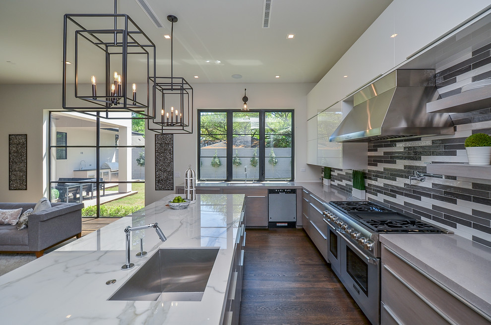 Example of a mid-sized transitional l-shaped medium tone wood floor open concept kitchen design in Houston with a single-bowl sink, flat-panel cabinets, white cabinets, marble countertops, multicolored backsplash, glass tile backsplash, stainless steel appliances, an island and white countertops