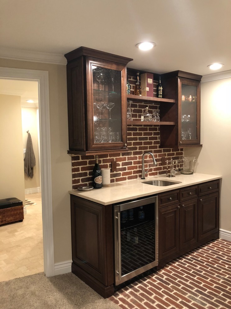 Inspiration for a large traditional single-wall seated home bar in Denver with an undermount sink, glass-front cabinets, dark wood cabinets, quartz benchtops, red splashback, brick splashback, brick floors and red floor.