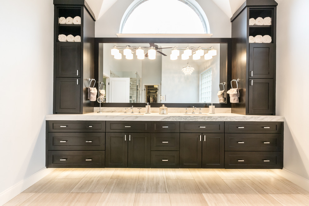 Inspiration for a large transitional master bathroom in Dallas with recessed-panel cabinets, dark wood cabinets, a corner shower, grey walls, porcelain floors, an undermount sink, quartzite benchtops, beige floor and a hinged shower door.