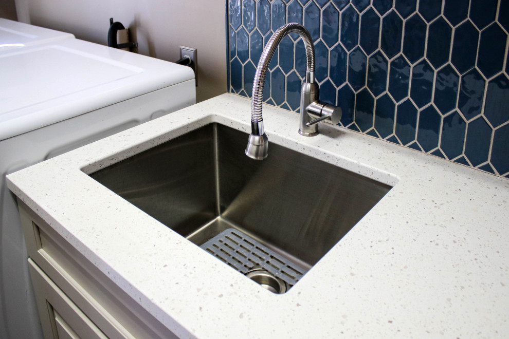 Exempel på en liten klassisk vita linjär vitt tvättstuga enbart för tvätt, med en undermonterad diskho, luckor med upphöjd panel, vita skåp, bänkskiva i kvarts, blått stänkskydd, stänkskydd i cementkakel, grå väggar och en tvättmaskin och torktumlare bredvid varandra