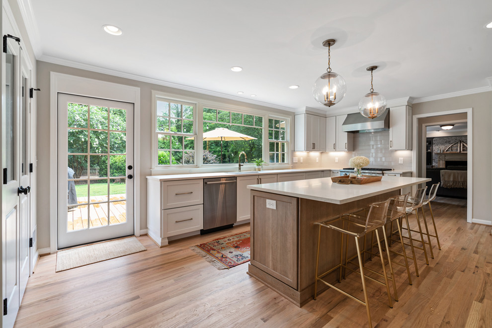 Transitional eat-in kitchen in Atlanta with an undermount sink, shaker cabinets, white cabinets, quartz benchtops, grey splashback, ceramic splashback, stainless steel appliances, light hardwood floors, with island, brown floor and white benchtop.