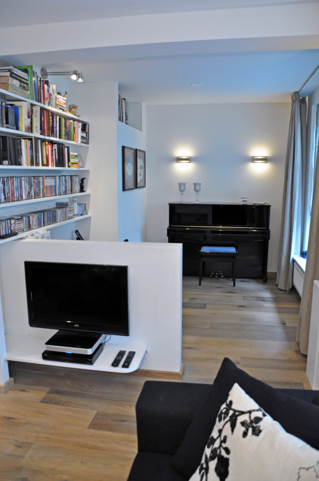 Foto på ett mellanstort funkis hemmabibliotek, med grå väggar, ljust trägolv, en standard öppen spis, en spiselkrans i gips, beiget golv och ett fristående skrivbord