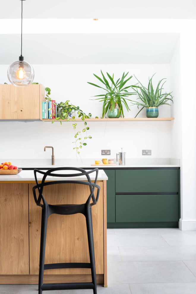 Zweizeilige Moderne Küche mit flächenbündigen Schrankfronten, grünen Schränken, Kücheninsel, grauem Boden und weißer Arbeitsplatte in London