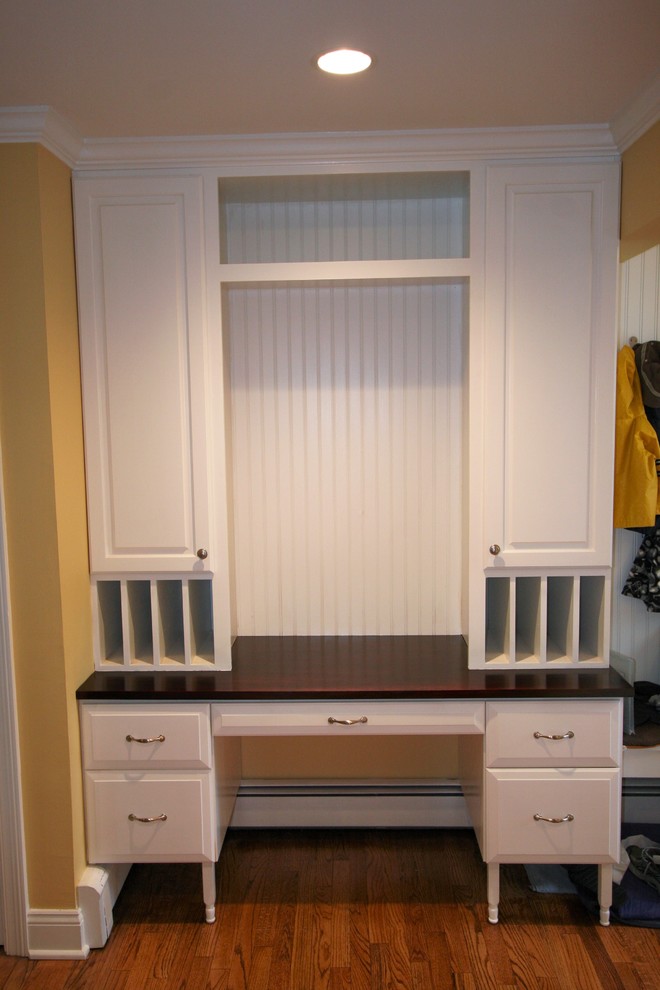 Photo of a mid-sized traditional mudroom in New York with yellow walls, medium hardwood floors and brown floor.