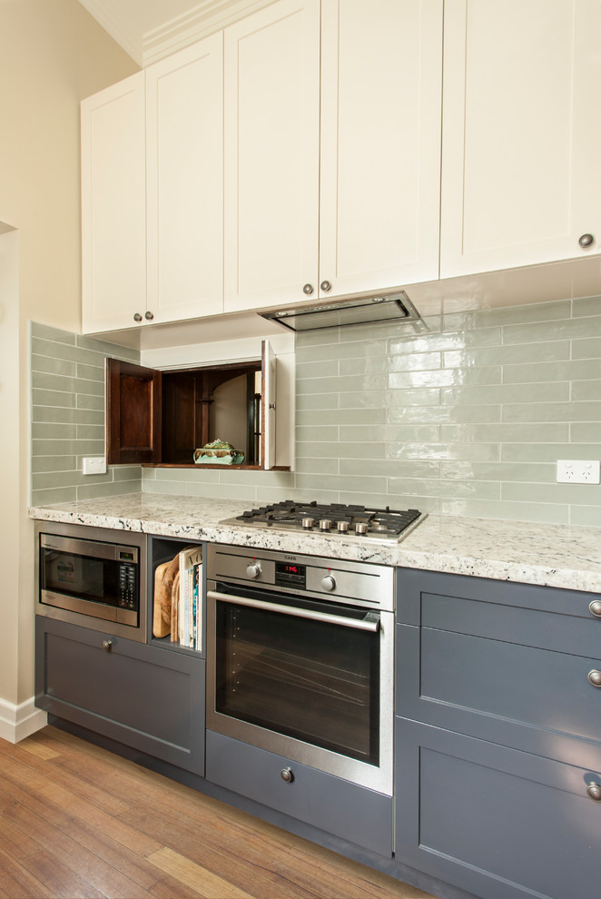 Photo of a mid-sized arts and crafts galley kitchen pantry in Melbourne with an undermount sink, recessed-panel cabinets, grey cabinets, granite benchtops, green splashback, subway tile splashback, stainless steel appliances, medium hardwood floors, no island and brown floor.