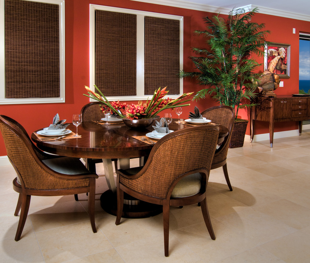 This is an example of a tropical open plan dining in Hawaii with red walls and limestone floors.