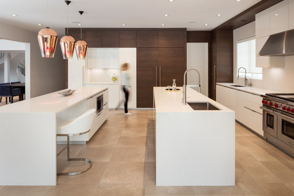 Photo of a contemporary kitchen in New York with an undermount sink, flat-panel cabinets, dark wood cabinets, panelled appliances, multiple islands and beige floor.