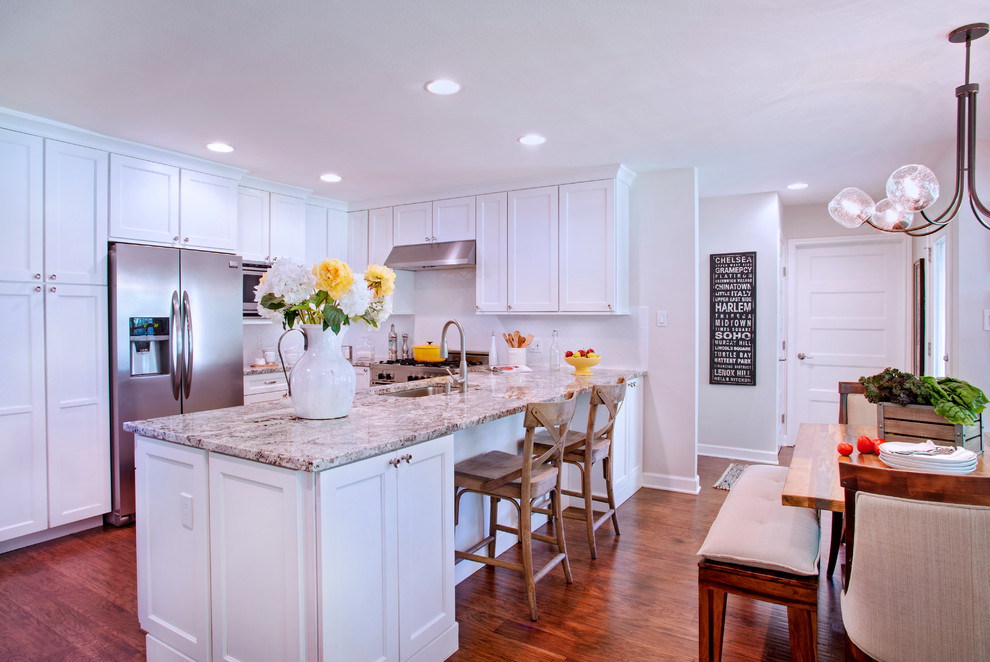 Example of a mid-sized transitional u-shaped medium tone wood floor eat-in kitchen design in Austin with a single-bowl sink, shaker cabinets, white cabinets, granite countertops, white backsplash, subway tile backsplash, stainless steel appliances and a peninsula