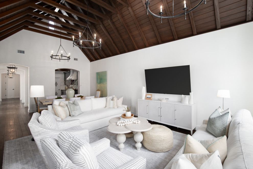 На фото: гостиная комната в морском стиле с белыми стенами, телевизором на стене и балками на потолке с