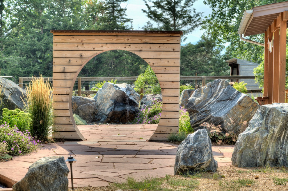 Cette photo montre un très grand xéropaysage arrière nature avec une exposition ensoleillée, des pavés en pierre naturelle et un portail.