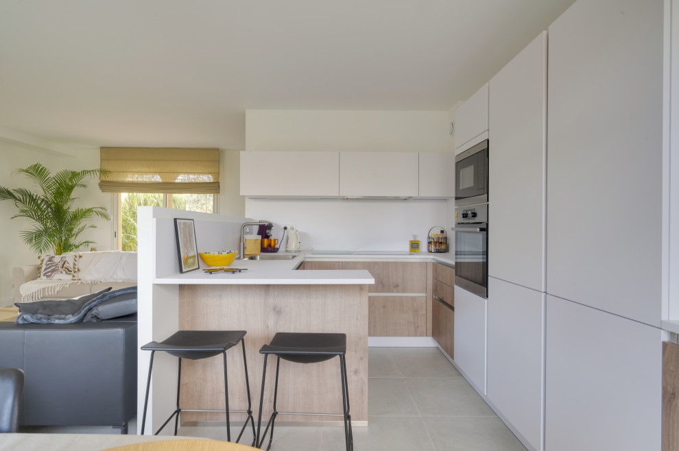 Design ideas for a small transitional u-shaped open plan kitchen in Montpellier with a single-bowl sink, beaded inset cabinets, medium wood cabinets, laminate benchtops, white splashback, timber splashback, panelled appliances, ceramic floors, beige floor and white benchtop.