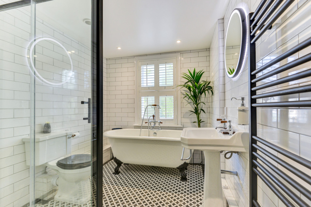 Photo of a medium sized victorian bathroom in Sussex with a freestanding bath, a corner shower, a two-piece toilet, white tiles, ceramic tiles, white walls, ceramic flooring, a pedestal sink, tiled worktops, multi-coloured floors, a sliding door, black worktops, feature lighting and a single sink.