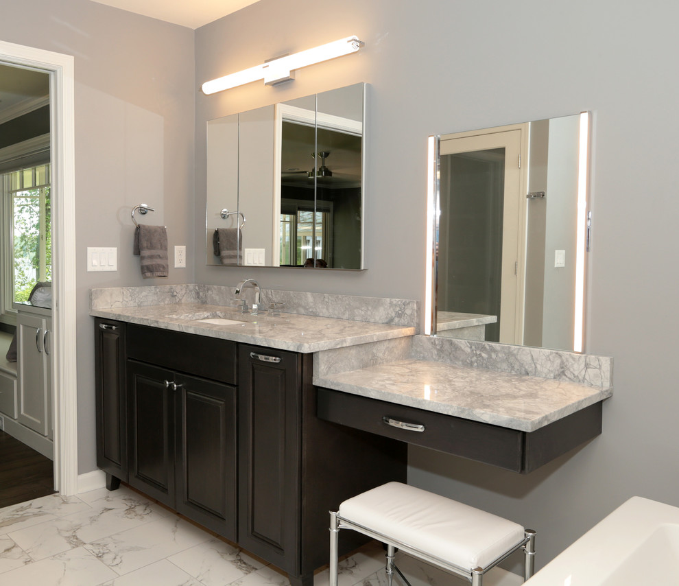 Large transitional gray tile and subway tile porcelain tile and white floor freestanding bathtub photo with raised-panel cabinets, gray cabinets, gray walls, an undermount sink and granite countertops