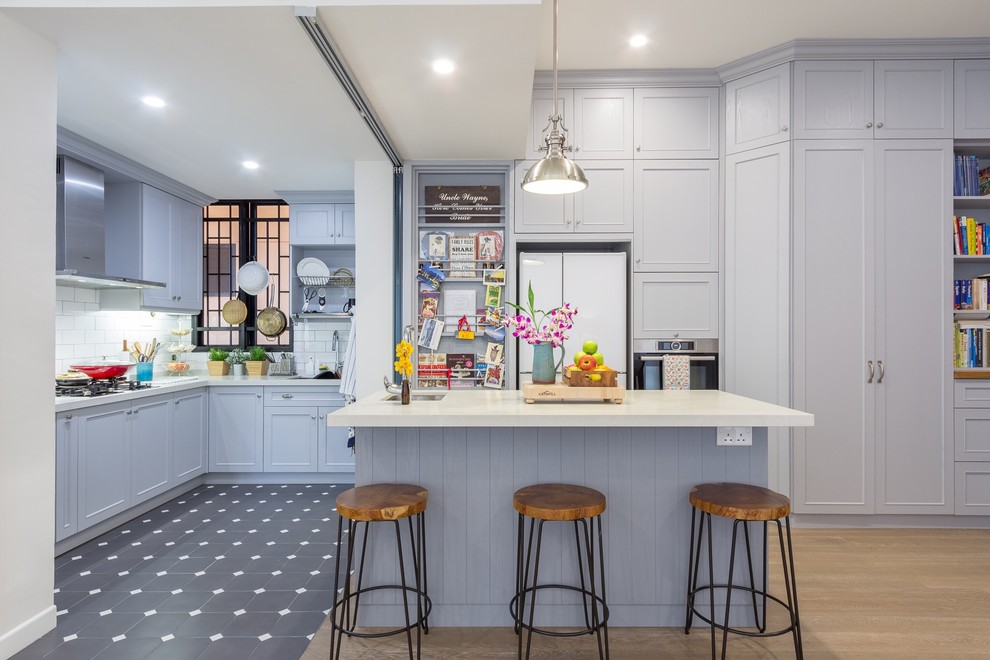 Photo of a transitional kitchen in Singapore with an undermount sink, recessed-panel cabinets, grey cabinets, white splashback, subway tile splashback, white appliances, medium hardwood floors and with island.