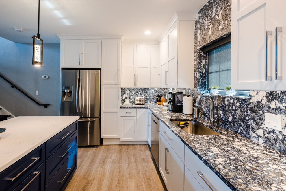 Inspiration for a mid-sized industrial l-shaped eat-in kitchen in Baltimore with an undermount sink, white cabinets, quartz benchtops, blue splashback, engineered quartz splashback, stainless steel appliances, vinyl floors, brown floor and blue benchtop.