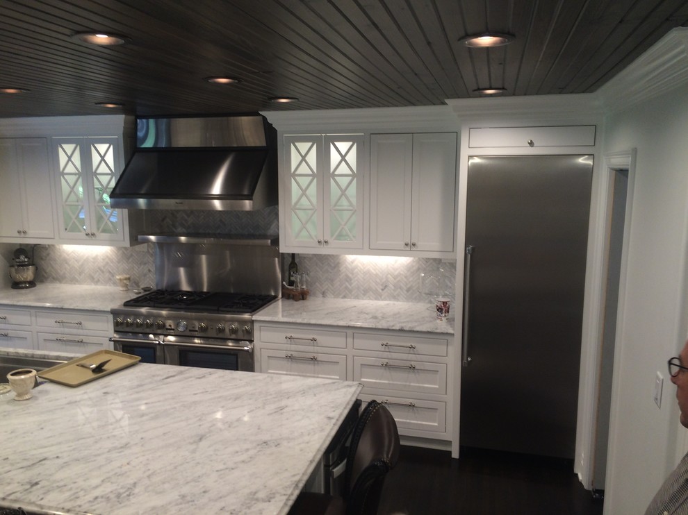 Large transitional l-shaped dark wood floor and brown floor eat-in kitchen photo with an undermount sink, beaded inset cabinets, white cabinets, quartzite countertops, white backsplash, marble backsplash, stainless steel appliances, an island and white countertops