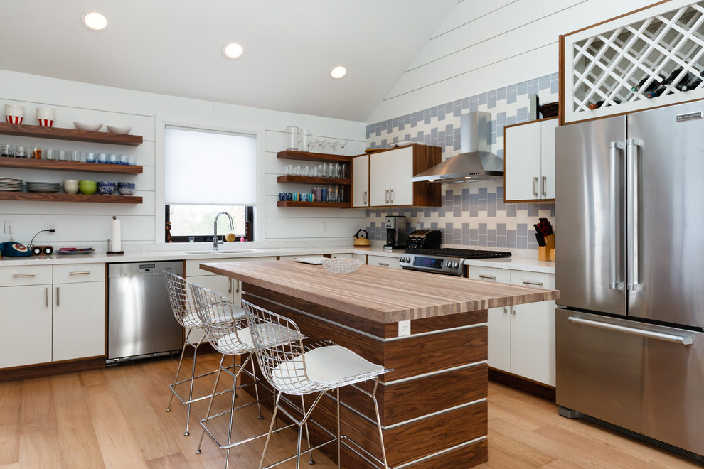 Small transitional light wood floor eat-in kitchen photo with a double-bowl sink, blue backsplash, stainless steel appliances and an island