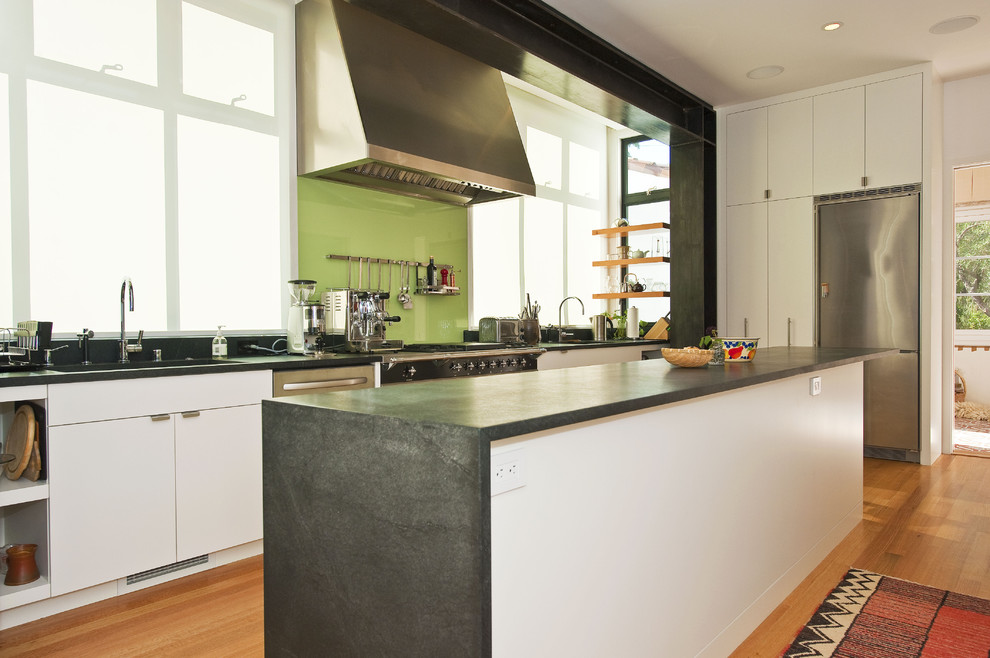 Contemporary kitchen in San Francisco with stainless steel appliances, flat-panel cabinets, white cabinets, green splashback, glass sheet splashback and soapstone benchtops.