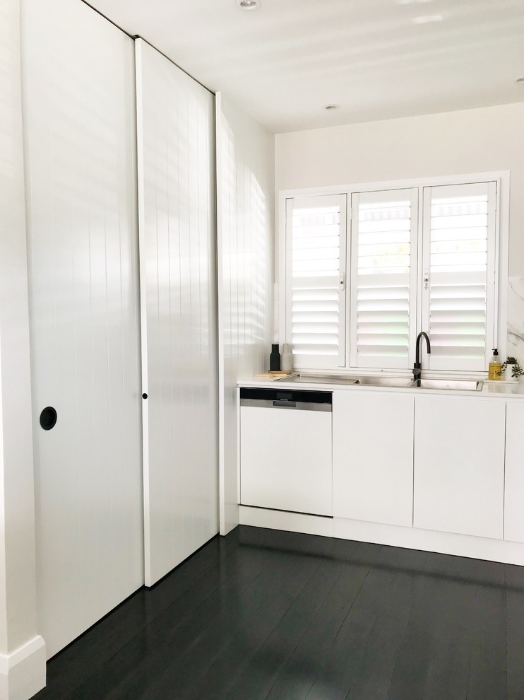 This is an example of a mid-sized modern u-shaped eat-in kitchen in Sydney with an undermount sink, flat-panel cabinets, white cabinets, quartz benchtops, multi-coloured splashback, marble splashback, stainless steel appliances, dark hardwood floors, with island and black floor.