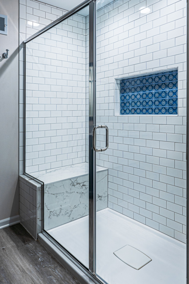 Inspiration for a mid-sized traditional master bathroom in Milwaukee with shaker cabinets, blue cabinets, an alcove shower, white tile, subway tile, beige walls, vinyl floors, an undermount sink, marble benchtops, brown floor, a hinged shower door, multi-coloured benchtops, a niche, a double vanity and a freestanding vanity.