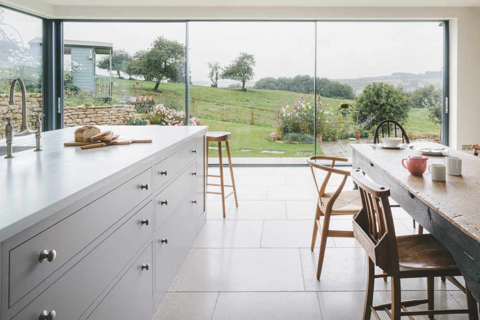 Design ideas for a large country l-shaped eat-in kitchen in Gloucestershire with a drop-in sink, shaker cabinets, blue cabinets, quartz benchtops, stainless steel appliances, limestone floors, with island and grey benchtop.