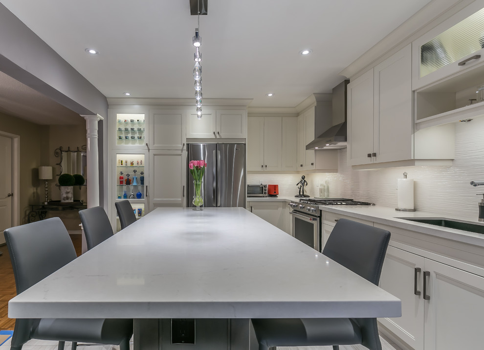 Eat-in kitchen - mid-sized transitional l-shaped porcelain tile eat-in kitchen idea in Toronto with a drop-in sink, recessed-panel cabinets, white cabinets, quartz countertops, stainless steel appliances and an island