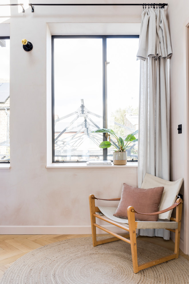 Design ideas for an industrial master bedroom in London with pink walls and light hardwood flooring.