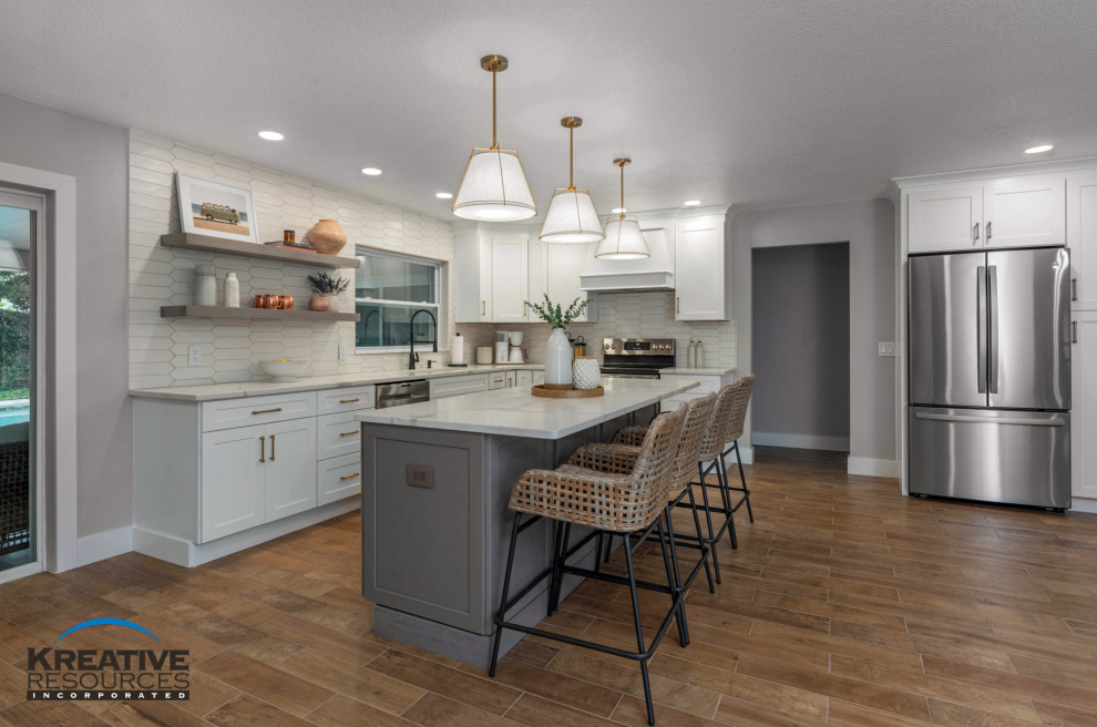 Eat-in kitchen - large transitional l-shaped porcelain tile and brown floor eat-in kitchen idea in Orlando with an undermount sink, shaker cabinets, quartzite countertops, beige backsplash, porcelain backsplash, stainless steel appliances, an island and white countertops