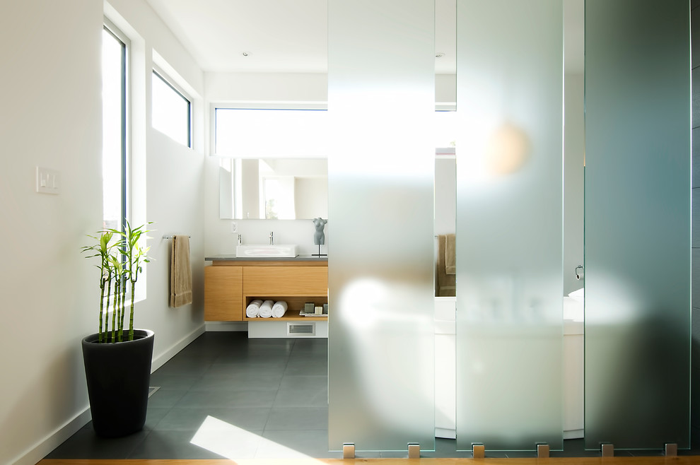 Modern bathroom in Ottawa with a vessel sink, flat-panel cabinets, medium wood cabinets and a freestanding tub.