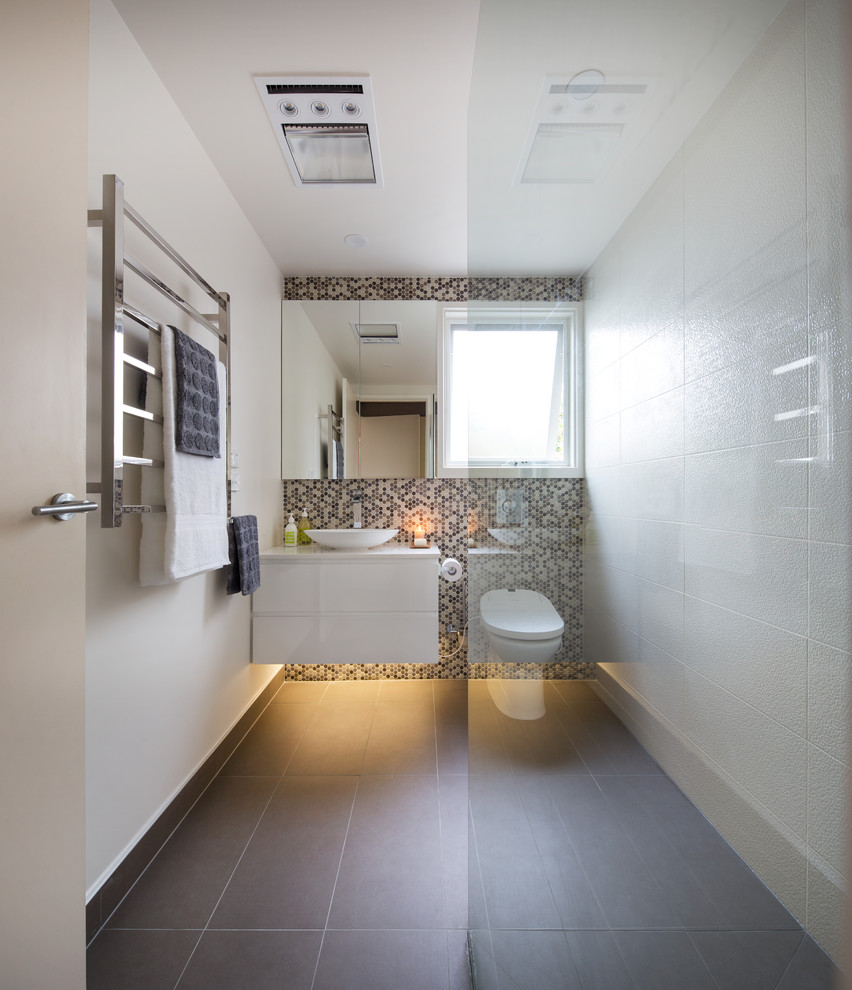 This is an example of a mid-sized modern master bathroom in Melbourne with raised-panel cabinets, white cabinets, an open shower, a two-piece toilet, gray tile, ceramic tile, white walls, porcelain floors, a vessel sink and quartzite benchtops.