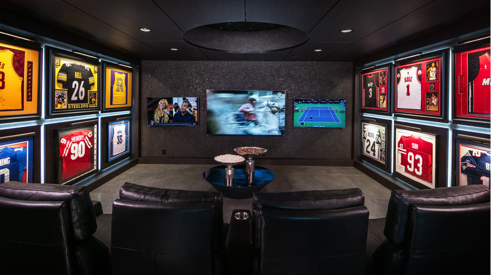 Photo of an industrial enclosed home theatre in Omaha with black walls, concrete floors, a wall-mounted tv and grey floor.