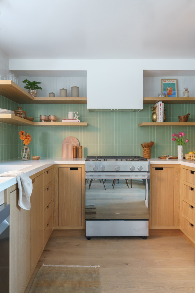 Foto på ett litet, avskilt funkis vit u-kök, med en undermonterad diskho, släta luckor, skåp i mellenmörkt trä, bänkskiva i kvarts, grönt stänkskydd, rostfria vitvaror, mellanmörkt trägolv och brunt golv